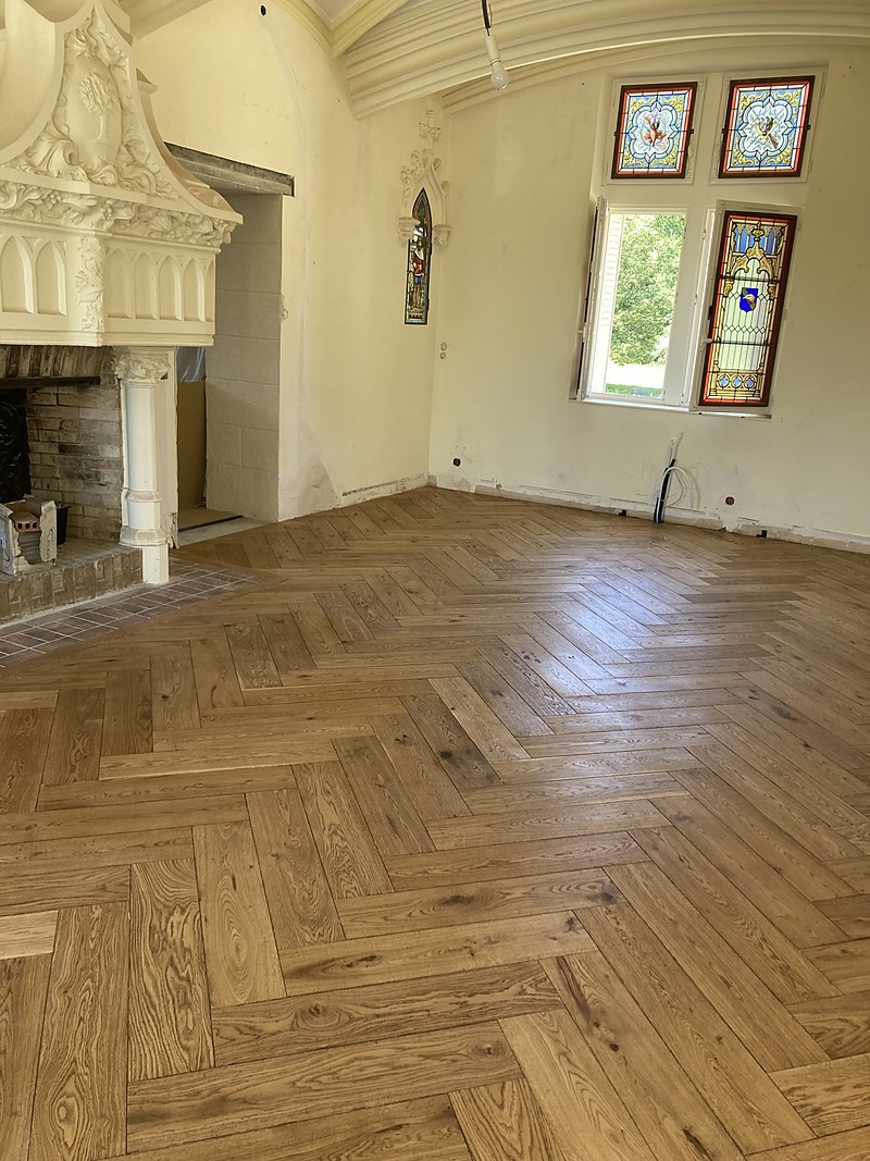 Parquet point de Hongrie en chêne dans une pièce d'époque ornée de vitraux : pose de parquet classique en Finistère.