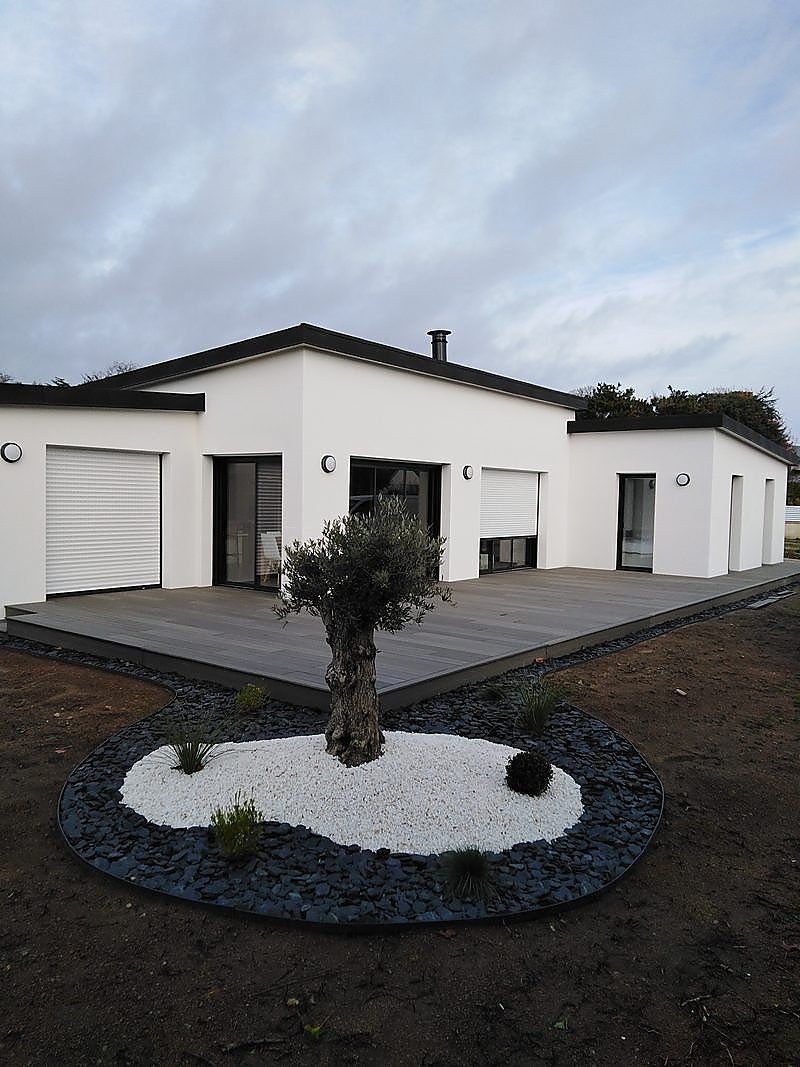 Terrasse périphérique en composite gris autour d'une maison contemporaine avec jardin minéral et olivier : tour de maison complet.
