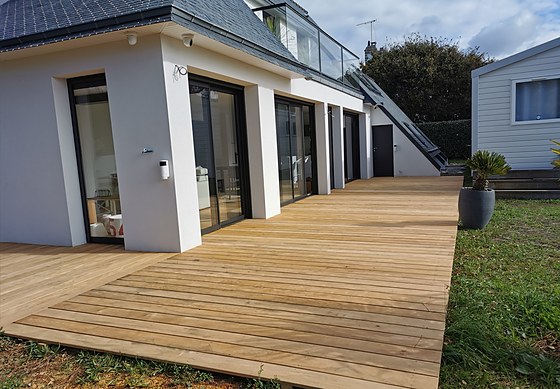 Grande terrasse bois périphérique en chêne thermo-traité vue du jardin : réalisation PMC dans le sud-Finistère.