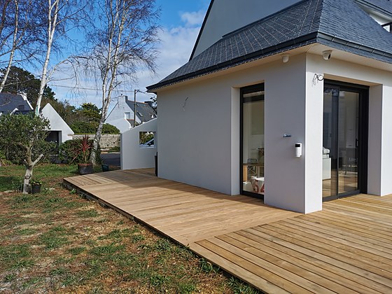 Terrasse en chêne thermo-traité au soleil rasant, vue depuis le pignon de la maison : terrasse bois sur mesure en Finistère.